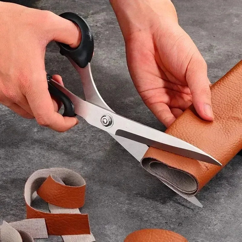 Person cutting brown leather with scissors on a gray surface