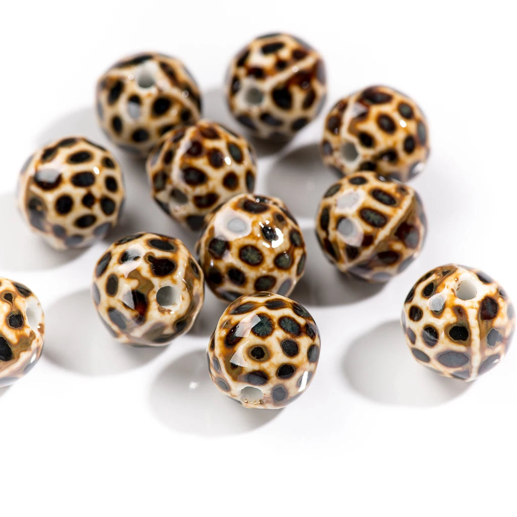 A group of round glass beads with a honeycomb pattern in black, dark brown, and cream on a white background.