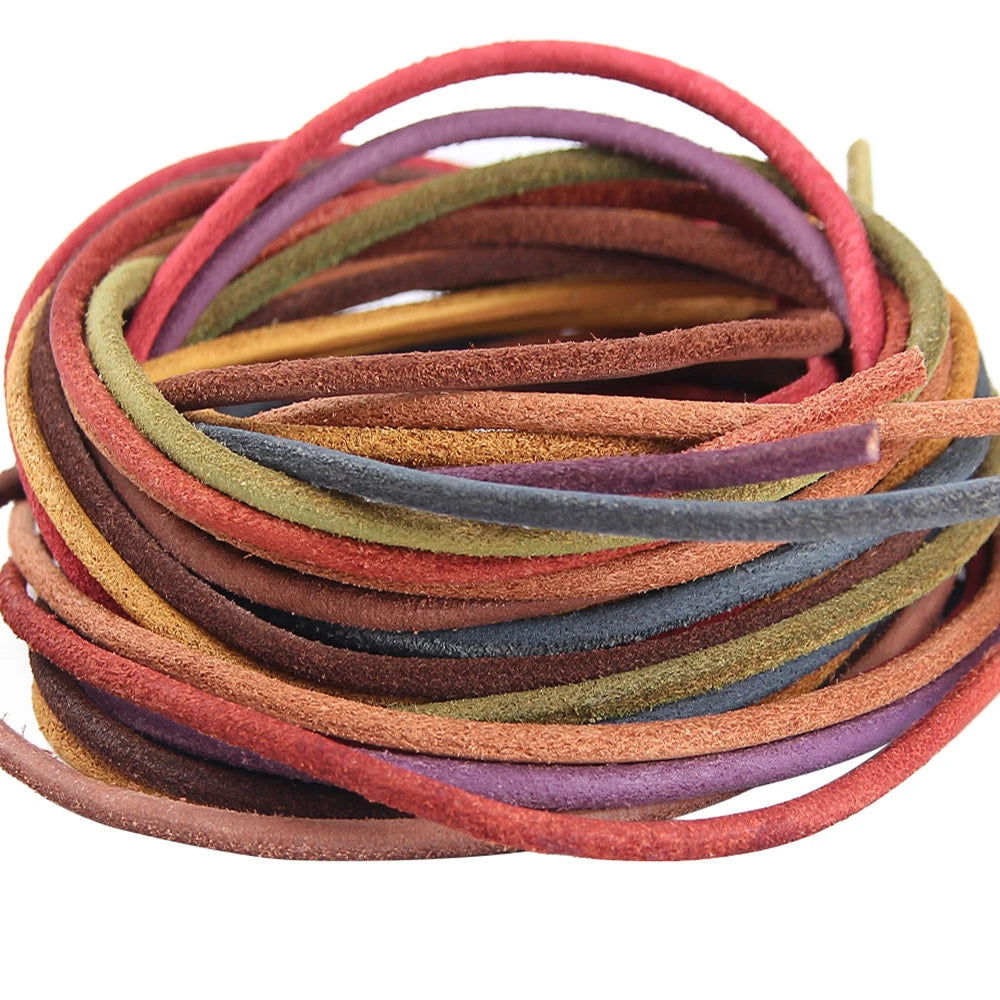 A coiled bundle of thin suede craft cords in assorted earthy and muted colors, including red, purple, olive green, mustard, brown, and blue-gray, photographed on a plain white background.