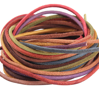 A coiled bundle of thin suede craft cords in assorted earthy and muted colors, including red, purple, olive green, mustard, brown, and blue-gray, photographed on a plain white background.