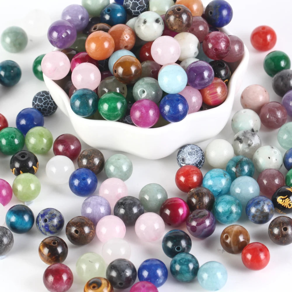 Assorted colored beads with a white bowl filled with them on a white background