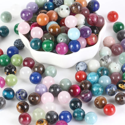 Assorted colored beads with a white bowl filled with them on a white background