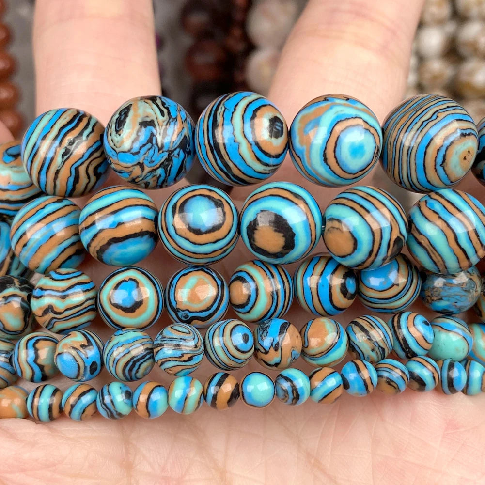 Close-up of multiple strands of round beads held in a hand. The beads have glossy marbled swirls of bright turquoise blue, black, and warm tan/brown.