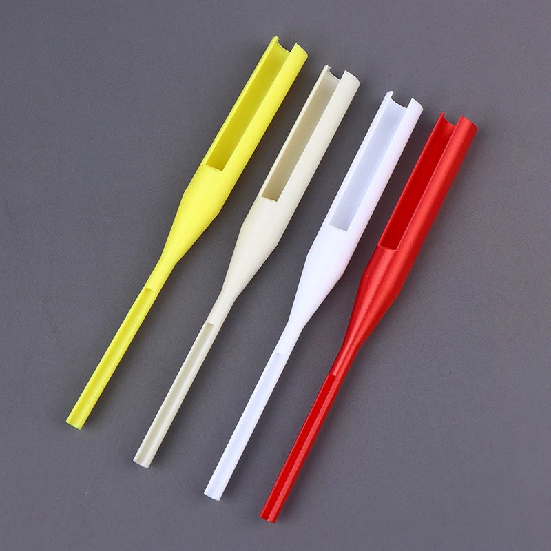 Four plastic fishing line guides in yellow, cream, white, and red, arranged diagonally on a dark gray background.