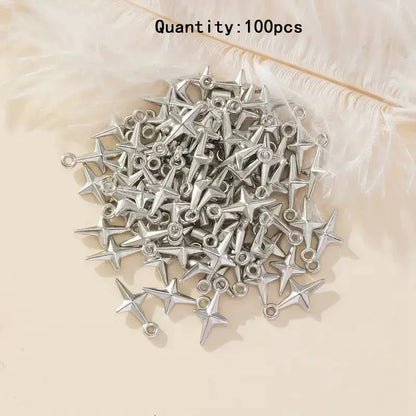A pile of 100 silver star-shaped jewelry charms with loops, displayed on a light beige surface with white feathers in the background.