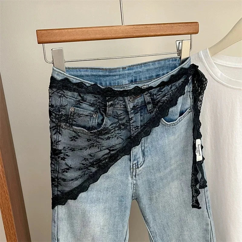 Blue jeans with black lace trim on a hanger against a neutral background
