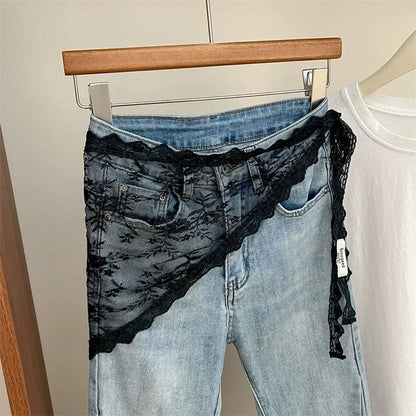 Blue jeans with black lace trim on a hanger against a neutral background