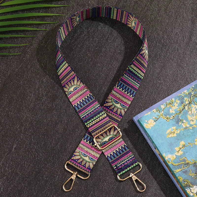 Colorful patterned strap with gold hardware on a dark surface next to a book with floral design
