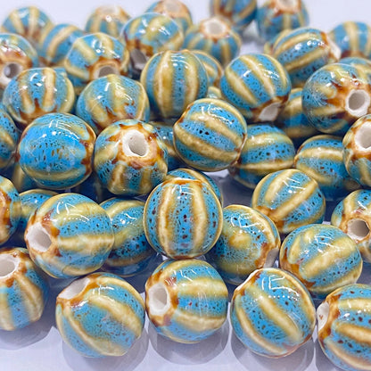 A pile of round ceramic beads with a glossy finish, featuring a mottled blue and beige striped pattern with small brown speckles and a central hole.