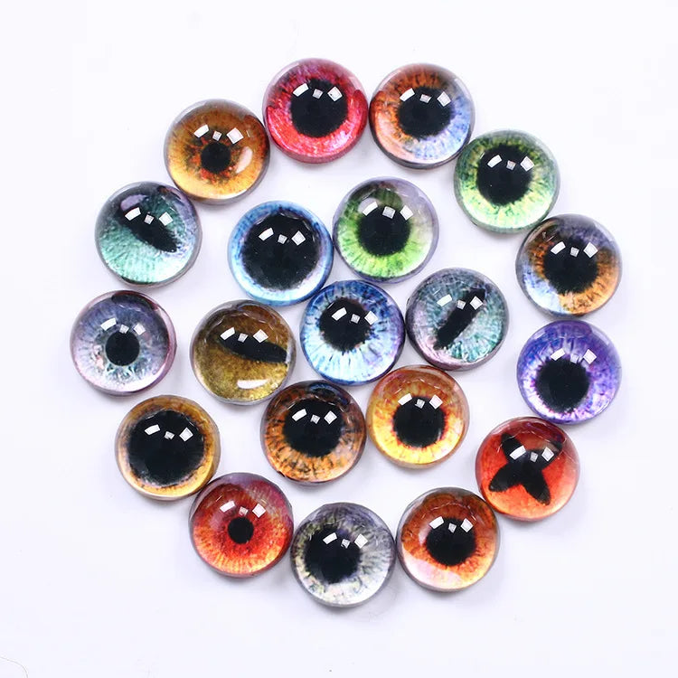 A group of round, glossy cabochon gemstones shaped like human eyes, displayed in a circular arrangement on a plain white background. The eyes feature various colors including brown, green, blue, red, purple, and gray, with detailed iris patterns and black pupils.