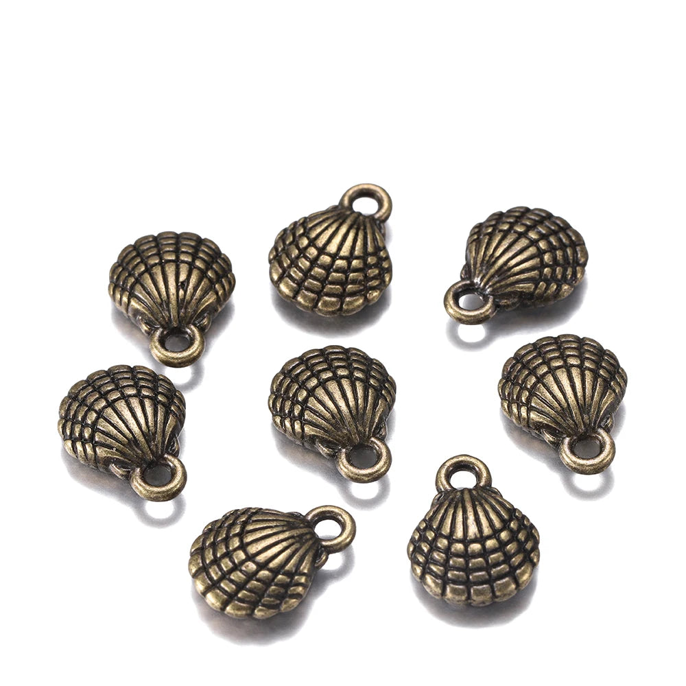 Nine antique bronze seashell-shaped jewelry charms with attached loops, arranged on a plain white background.