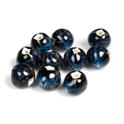 Nine round glass beads with a marbled pattern of black, deep blue, and white, arranged on a plain white background.