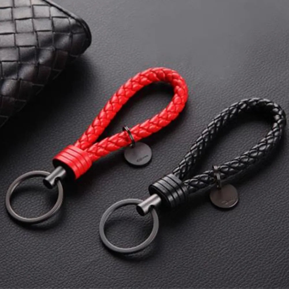 Two braided keychains, one red and one black, on a dark textured surface.