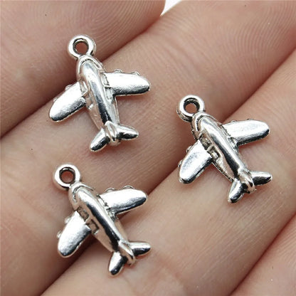 Three silver airplane charms on a person's hand