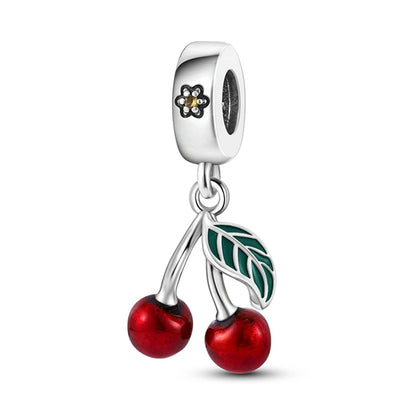 Silver charm with red cherries and a green leaf on a white background