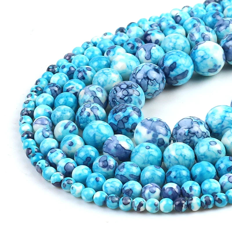 Multiple strands of round turquoise-blue marbled beads with dark blue and white veining, arranged in a curved coil on a white background.