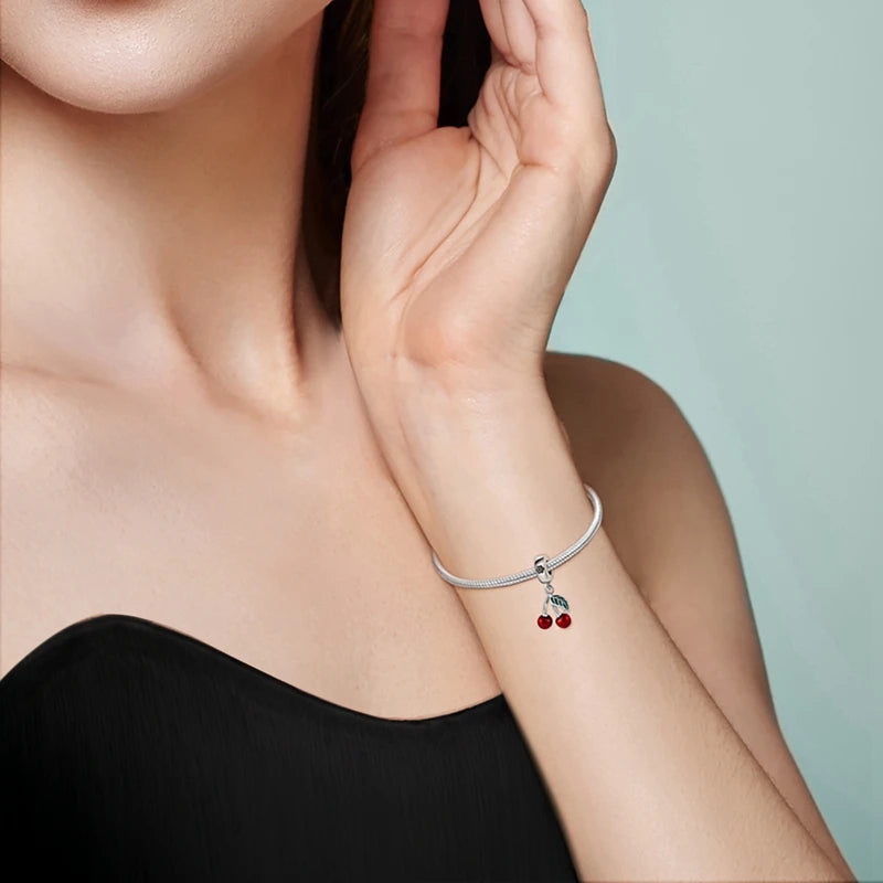 Silver bracelet with charms on a person's wrist against a light background