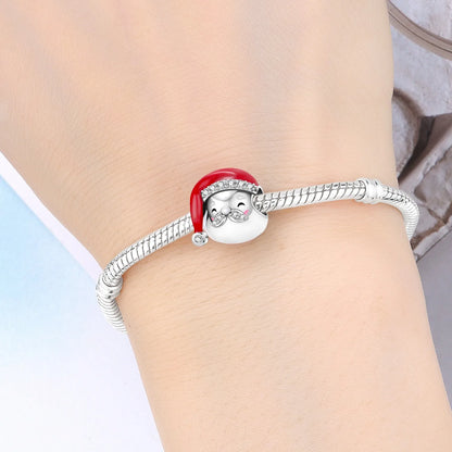 A silver-toned snake-style bracelet worn on a wrist, featuring a round white penguin charm wearing a red Santa hat with small clear rhinestone accents.