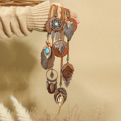 Decorative wall hanging with feathers and beads against a beige background