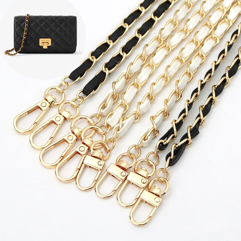 Gold chain purse straps with black and white leather ends on a white background