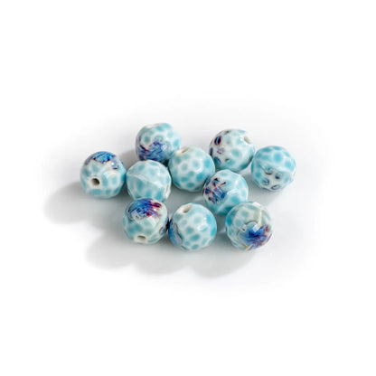 A group of small round glass beads with a light blue and white spotted pattern and blue floral accents, arranged on a plain white background.