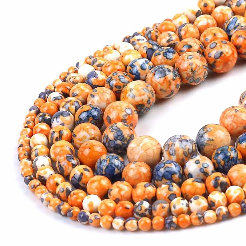 Marbled gemstone beads in orange, cream, and dark blue, arranged in a spiral on a white background.