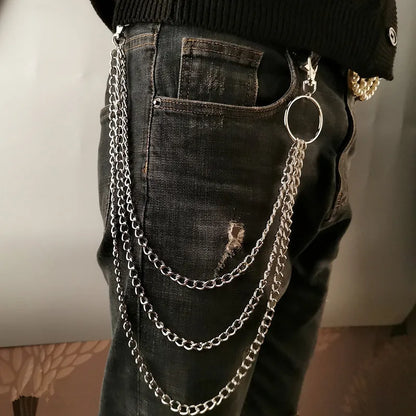 Person wearing black jeans with silver chain details on a neutral background