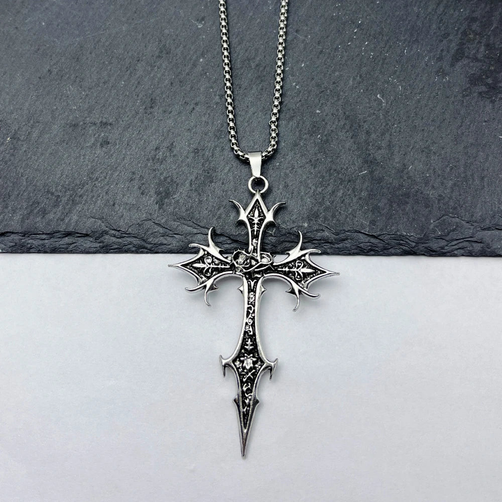 Silver cross pendant necklace on a dark stone surface