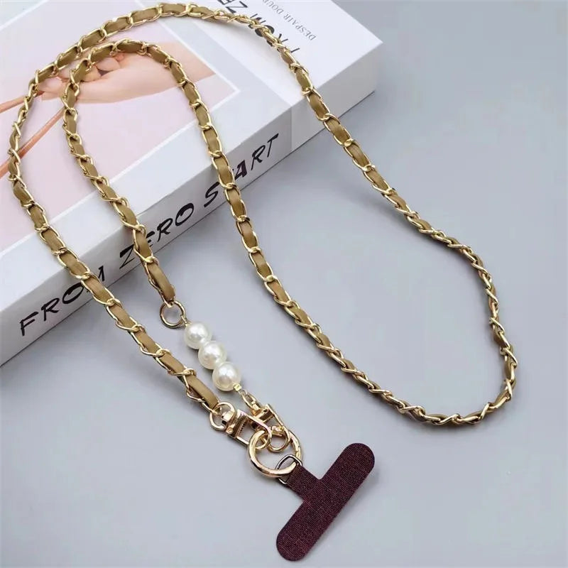 Gold chain necklace with a pearl charm and red leather tag on a light gray background