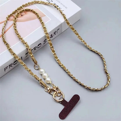 Gold chain necklace with a pearl charm and red leather tag on a light gray background