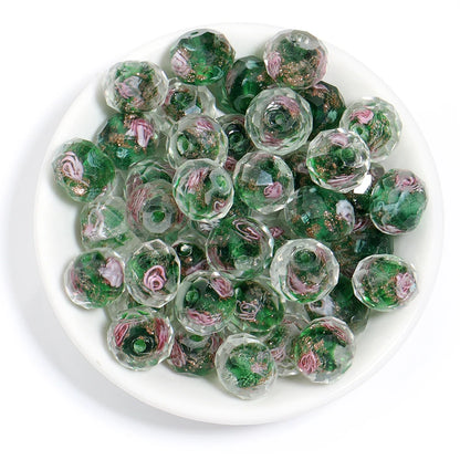 Green glass marbles with pink floral designs on a white plate