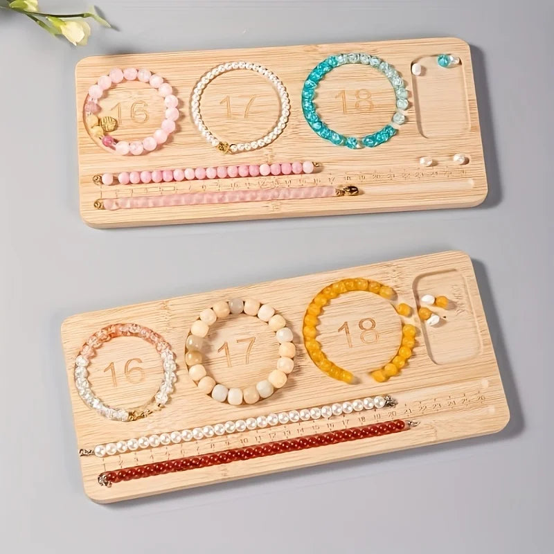 Two bamboo jewelry organizer trays on a light gray background, each holding numbered beaded bracelets and small jewelry pieces. The bracelets include pink, turquoise, cream, yellow, and red tones.