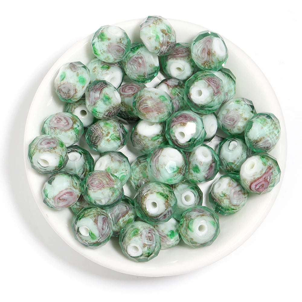 A pile of round glass beads with a swirled pattern of green, white, and dusty pink, displayed on a white plate against a white background.