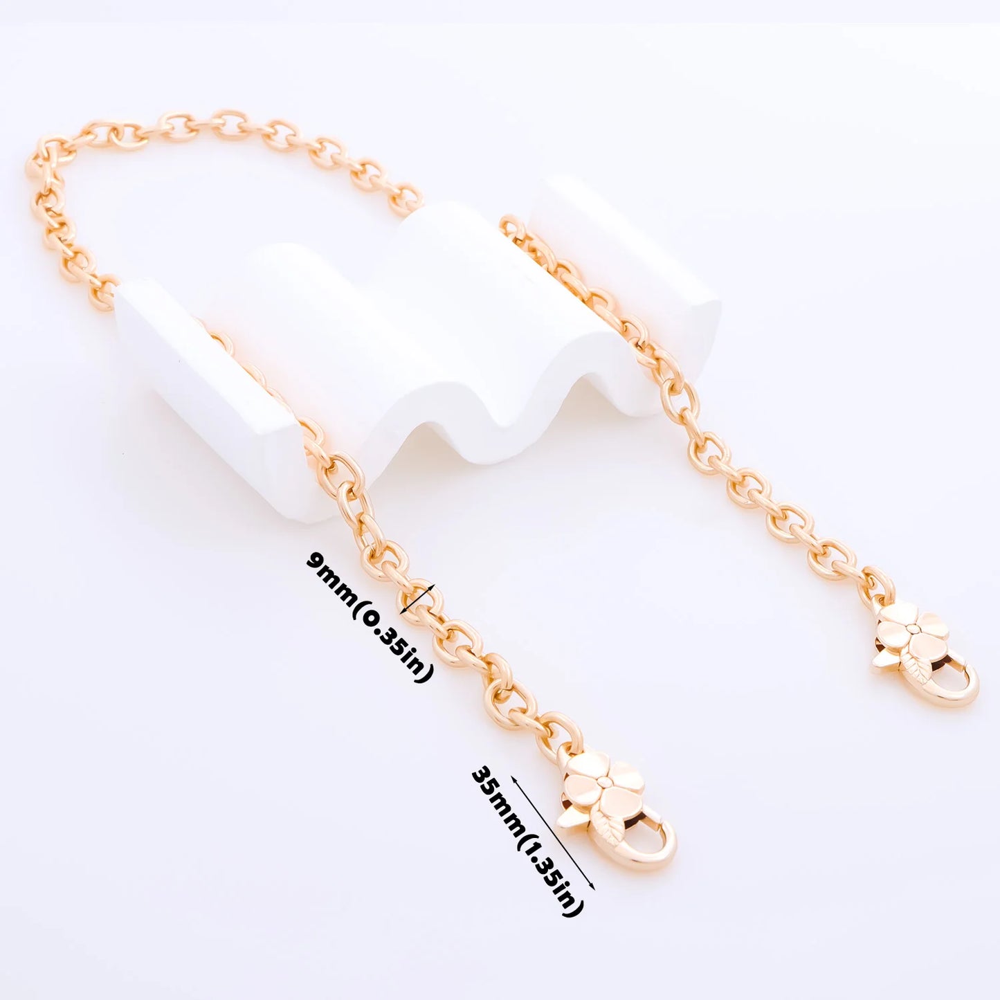 A gold-tone chain extender strap with a lobster clasp and flower charm, displayed on a white background with dimension labels showing 9mm and 35mm.
