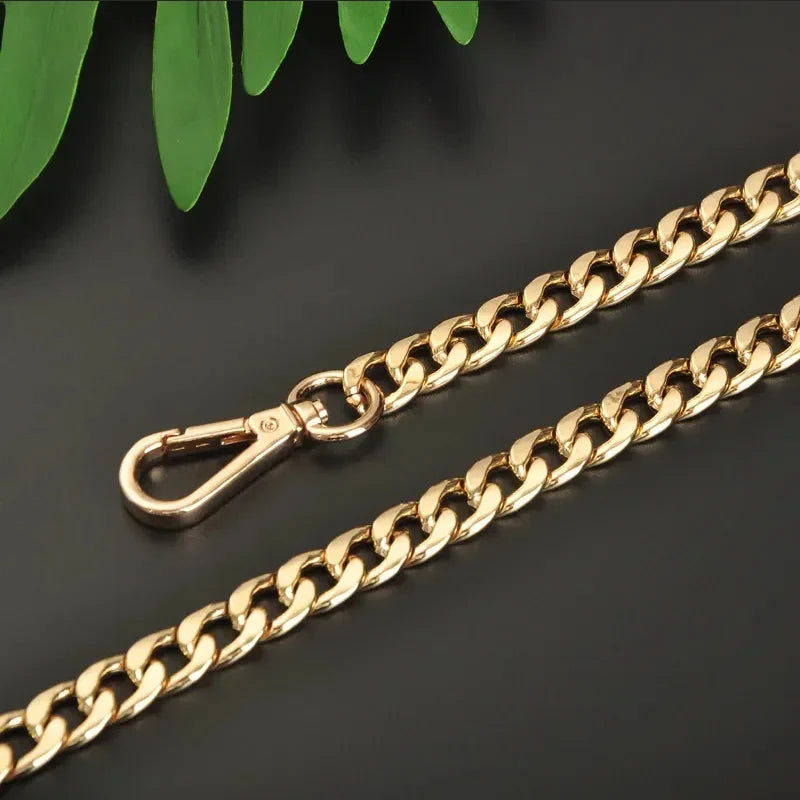 Gold chain with clasp on a dark surface with green leaves
