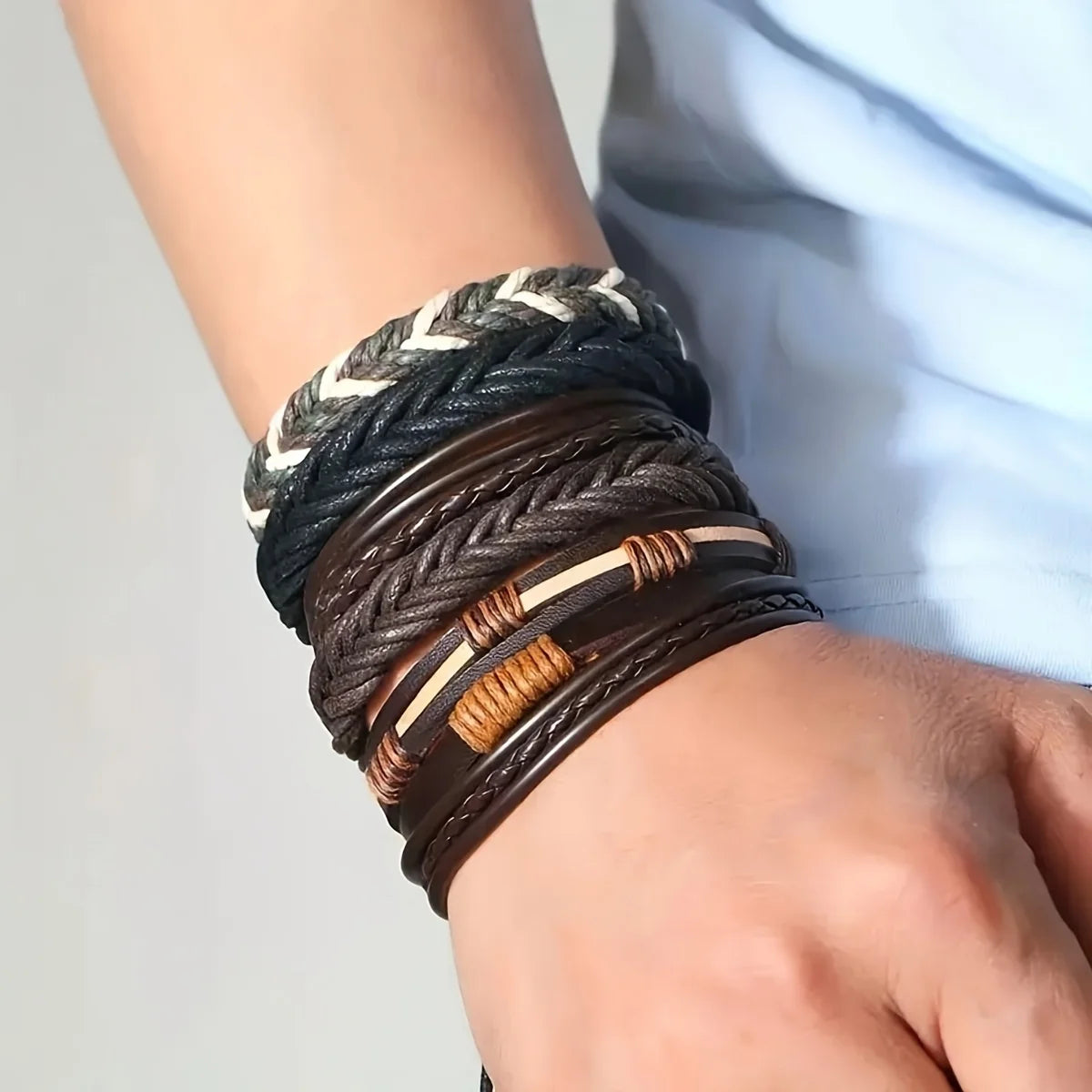 Close-up of a wrist wearing multiple braided leather bracelets with metal accents.
