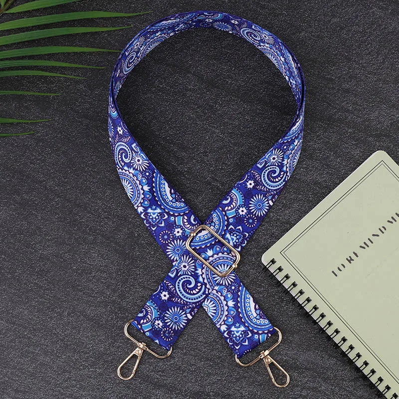 Blue paisley patterned strap with gold hardware on a dark surface