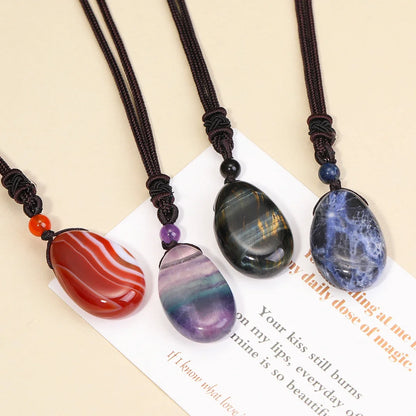 Three stone pendants on black cords with a decorative card underneath