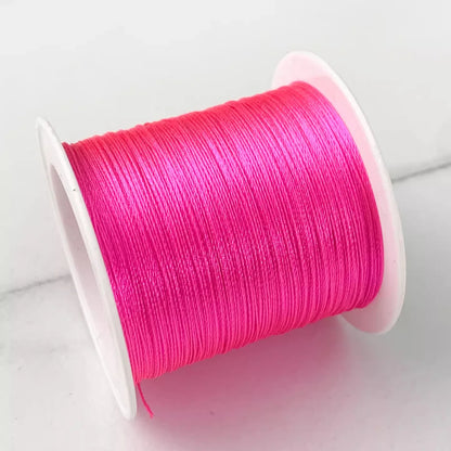A spool of bright hot pink embroidery thread wound tightly on a white plastic spool, set against a clean white background.