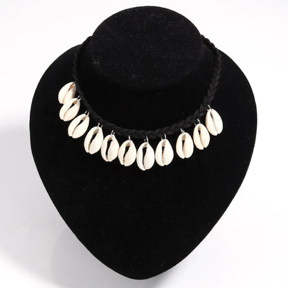 Necklace with cowrie shells on a black velvet stand against a white background