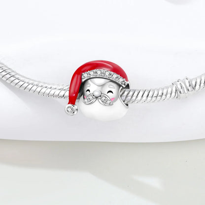 A silver-toned charm bracelet featuring a penguin wearing a red Santa hat with clear rhinestone trim, shown on a white background.
