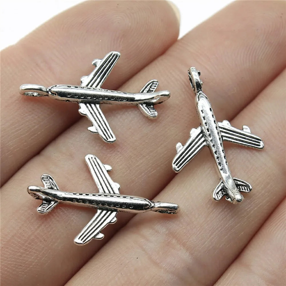 Three silver airplane pendants on a hand