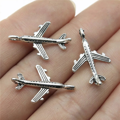 Three silver airplane pendants on a hand