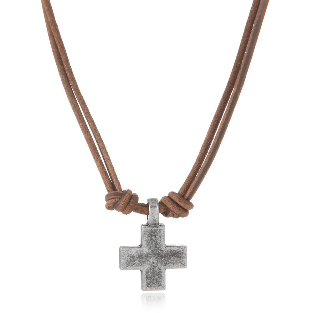 A silver cross pendant necklace on a brown double-strand cord, shown against a plain white background.