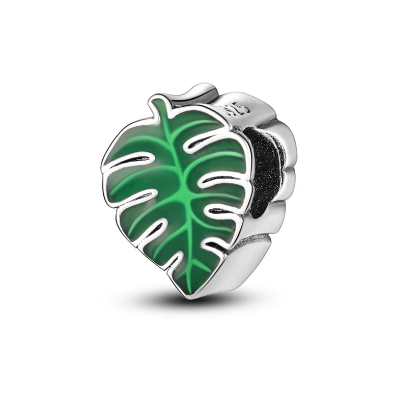 Silver charm with green leaf design on a white background