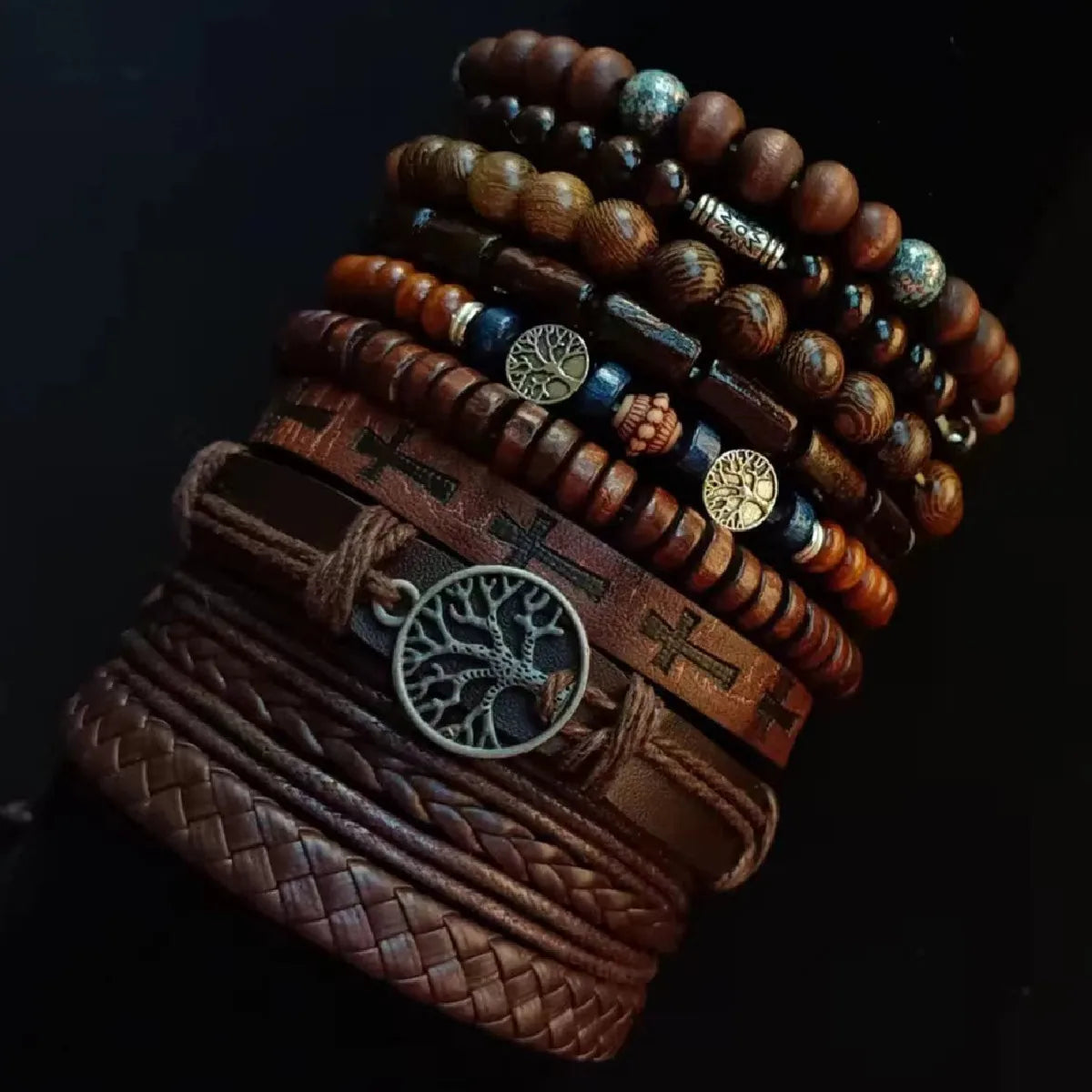 Stack of wooden and leather bracelets with various charms on a dark background