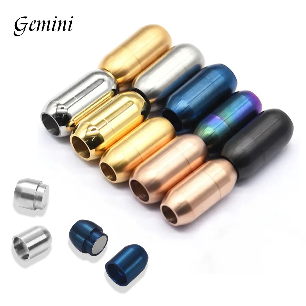 Twelve metallic capsule-shaped jewelry clasps arranged on a white background, including gold, silver, blue, rose gold, black, and iridescent finishes, with three loose blue stoppers shown in front. The word Gemini appears in the top left.