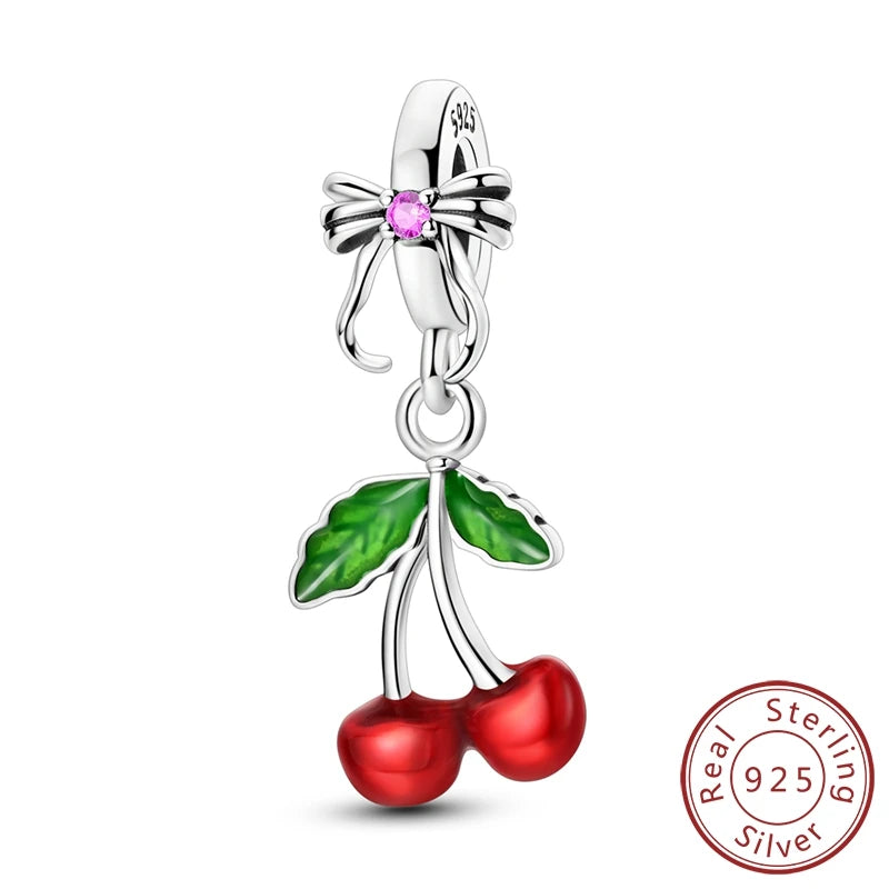 Silver charm with red cherries and green leaves on a white background