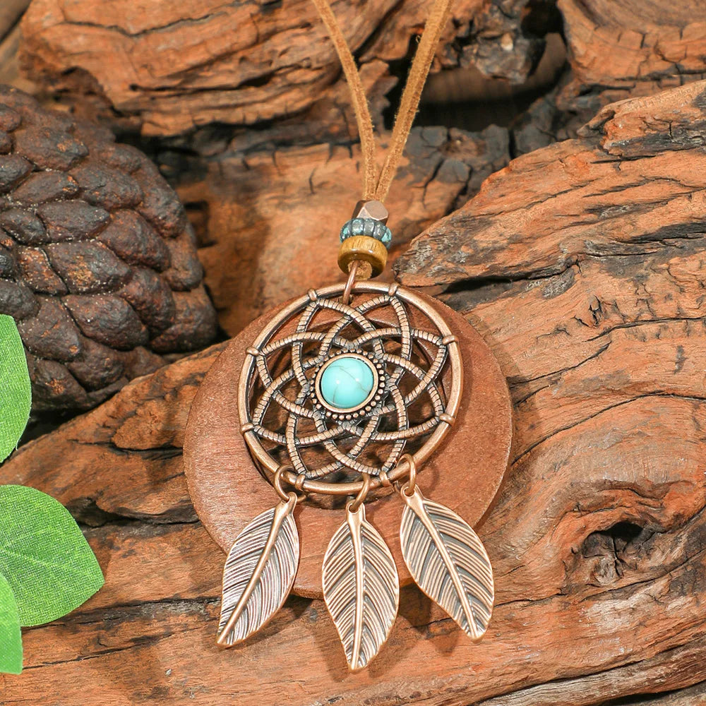 Dreamcatcher pendant with turquoise stone and feathers on a wooden background