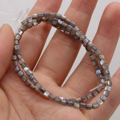 Three strands of small gray faceted shell beads with a silver clasp, held in a person's hand.